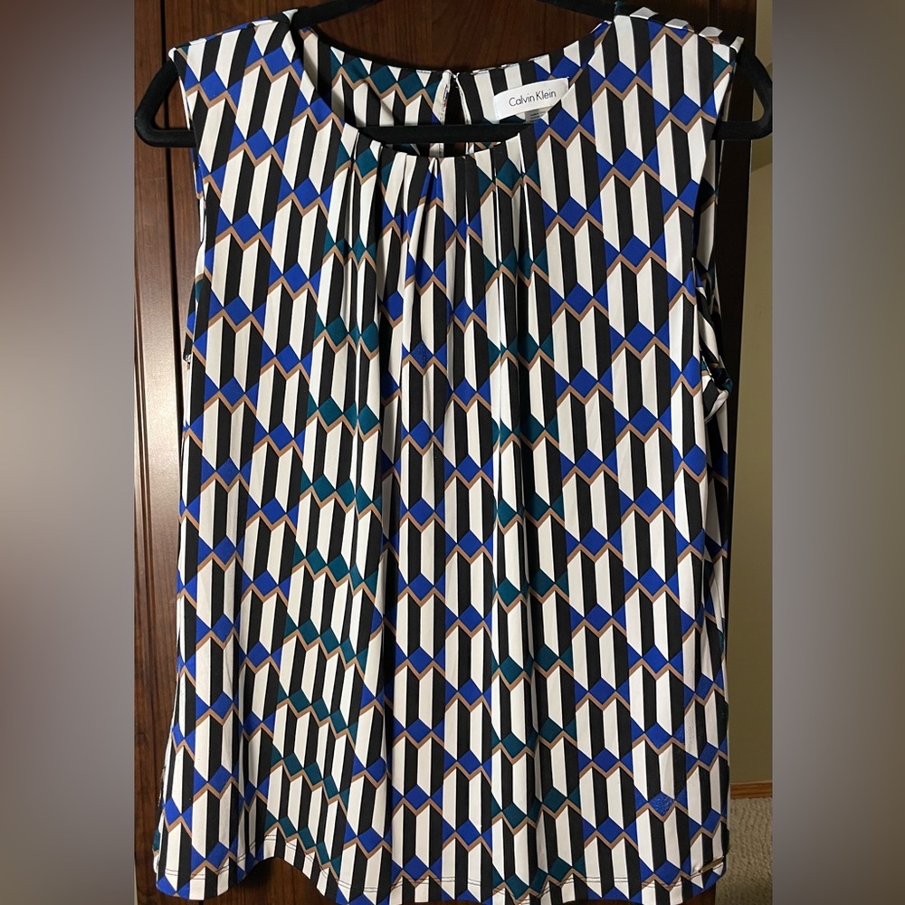 Sleeveless blouse with open pleats at neck and a small button on the back.